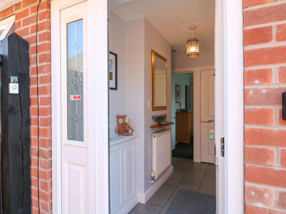 An entrance hallway with a mirror and radiator at Pinecote Cottage in Nottingham