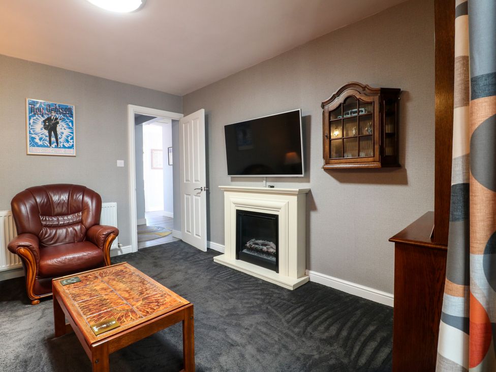 A living room with a leather chair and coffee table at Pinecote Cottage in Nottingham