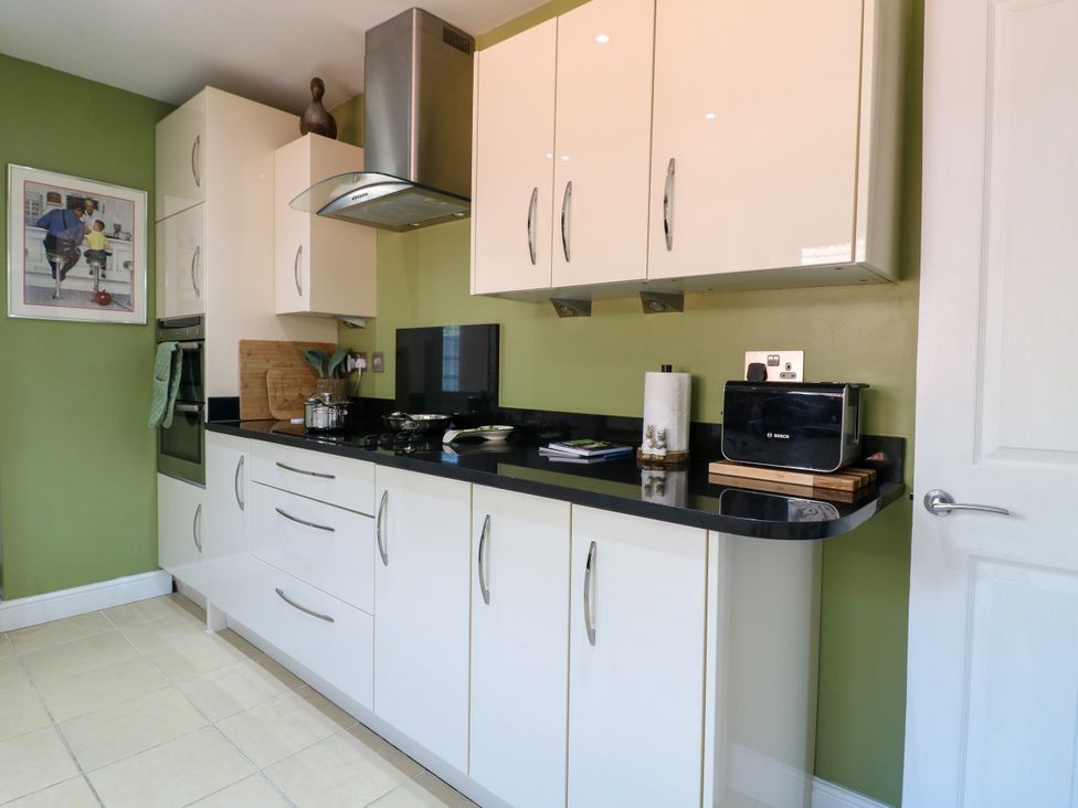 A kitchen with cabinets and appliances at Pinecote Cottage, Nottingham