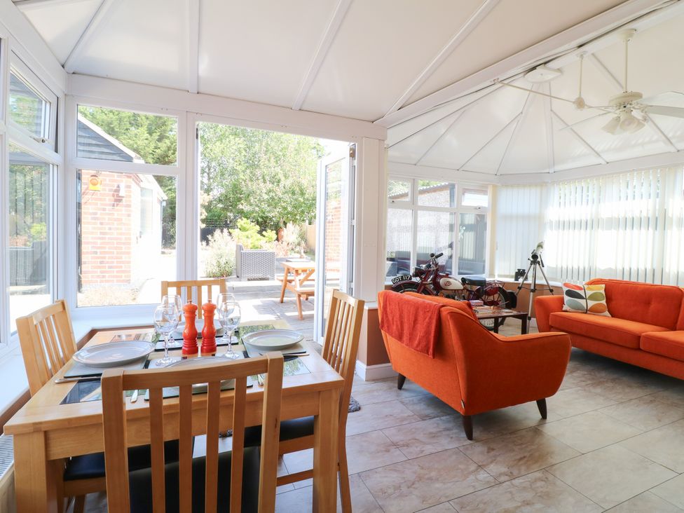 A conservatory with a dining table and seating area at Pinecote Cottage Nottingham