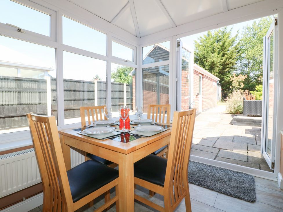 A dining table set with plates and glasses in a conservatory at Pinecote Cottage Nottingham