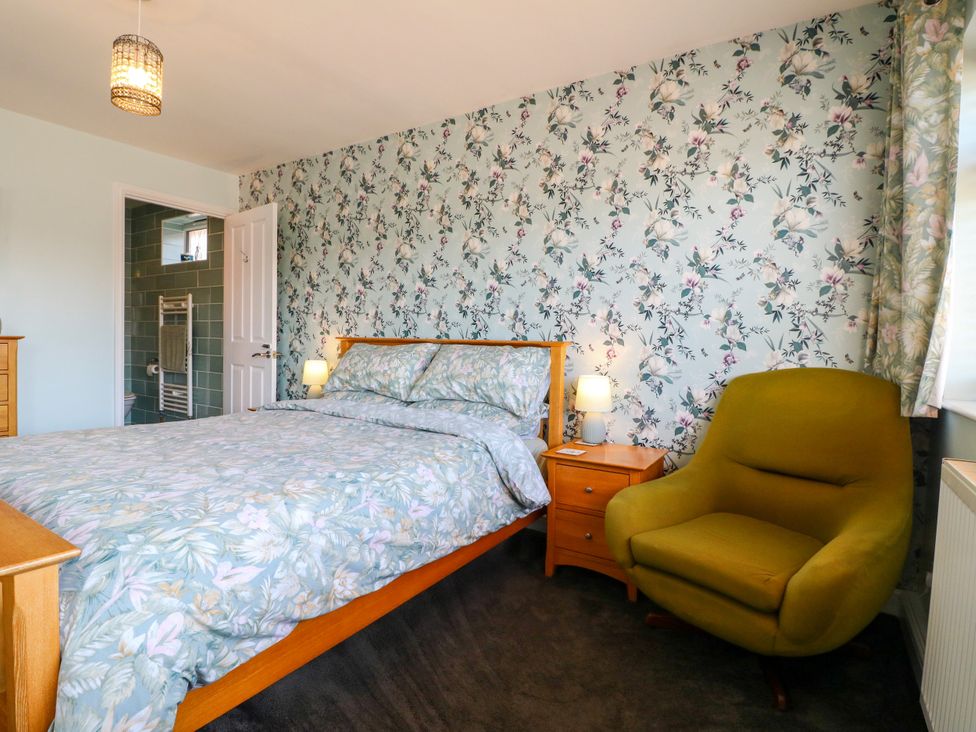 A bedroom with a bed and a chair at Pinecote Cottage Nottingham