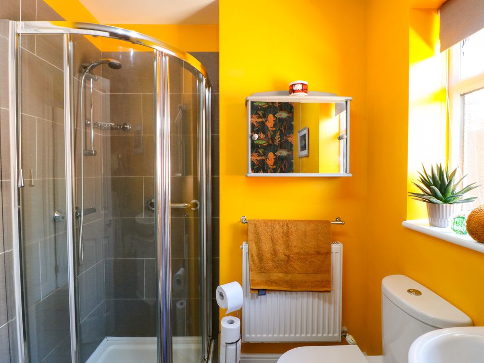 A bathroom with a shower, toilet, and mirror at Pinecote Cottage Nottingham