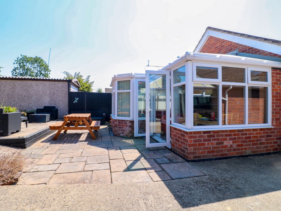 A conservatory opening to a patio with a table and chairs at Pinecote Cottage Nottingham