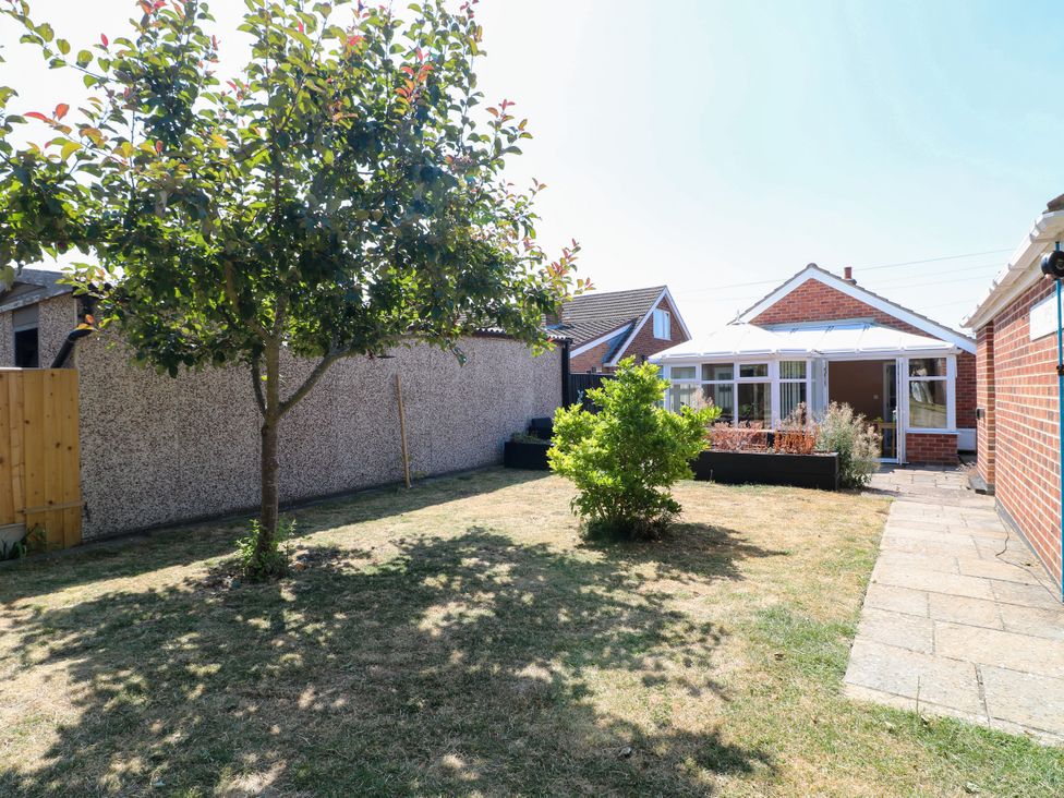A garden with a tree and house at Pinecote Cottage Nottingham