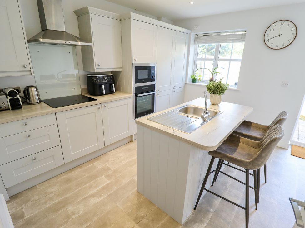 A kitchen with a sink and bar stools at Burton Fields in Brandesburton