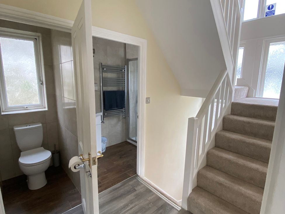 A hallway with a staircase and a bathroom door at Nesden House