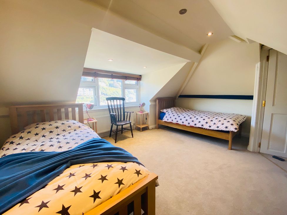 A bedroom with two beds and a chair at Harbour Lodge in Looe