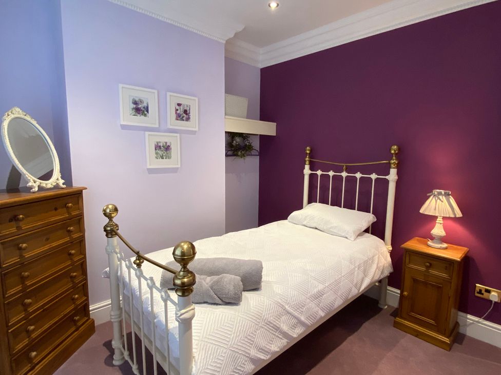 A bedroom with a single bed and dresser at Harbour Lodge in Looe