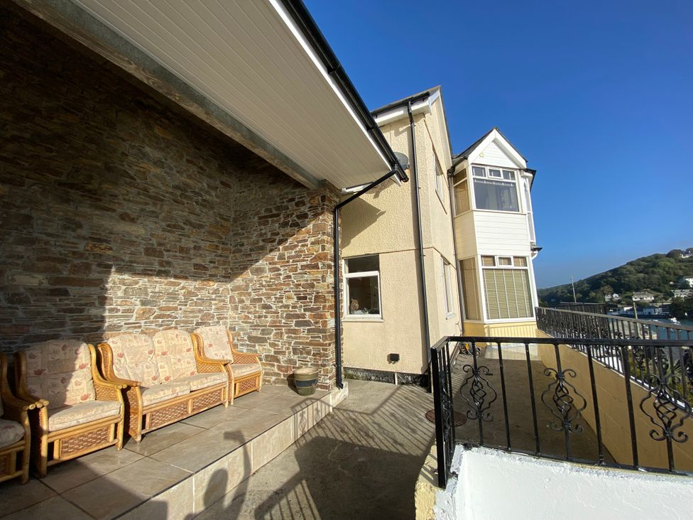 An outdoor seating area with a stone wall and sofas at Harbour Lodge in Looe