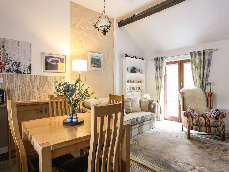 A living room with a dining table and chairs at Riverside Cottage in Caernarfon