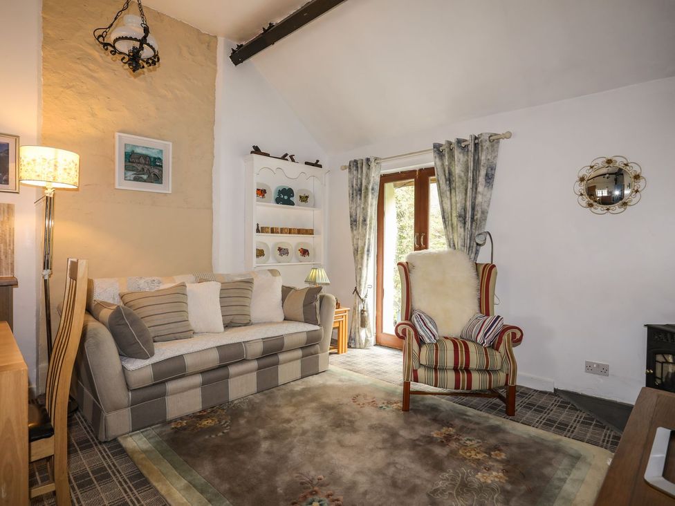 A living room with a sofa, chair and shelves at Riverside Cottage in Caernarfon