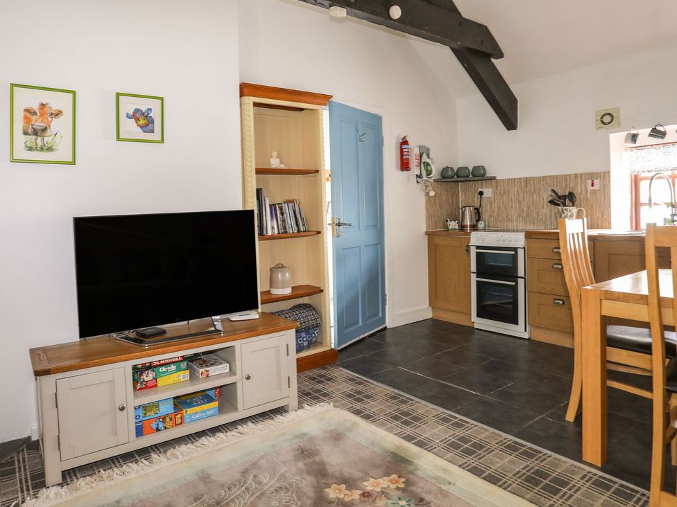 A living room with a TV and kitchen area at Riverside Cottage in Caernarfon