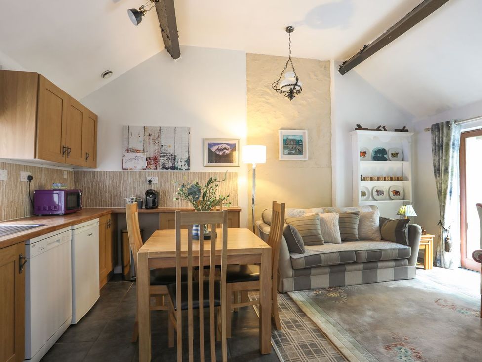 A living room with a dining table and kitchen cabinets at Riverside Cottage in Caernarfon