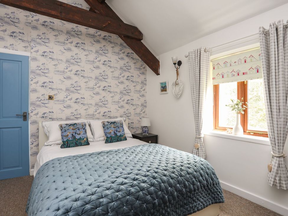 A bedroom with a bed and window at Riverside Cottage in Caernarfon