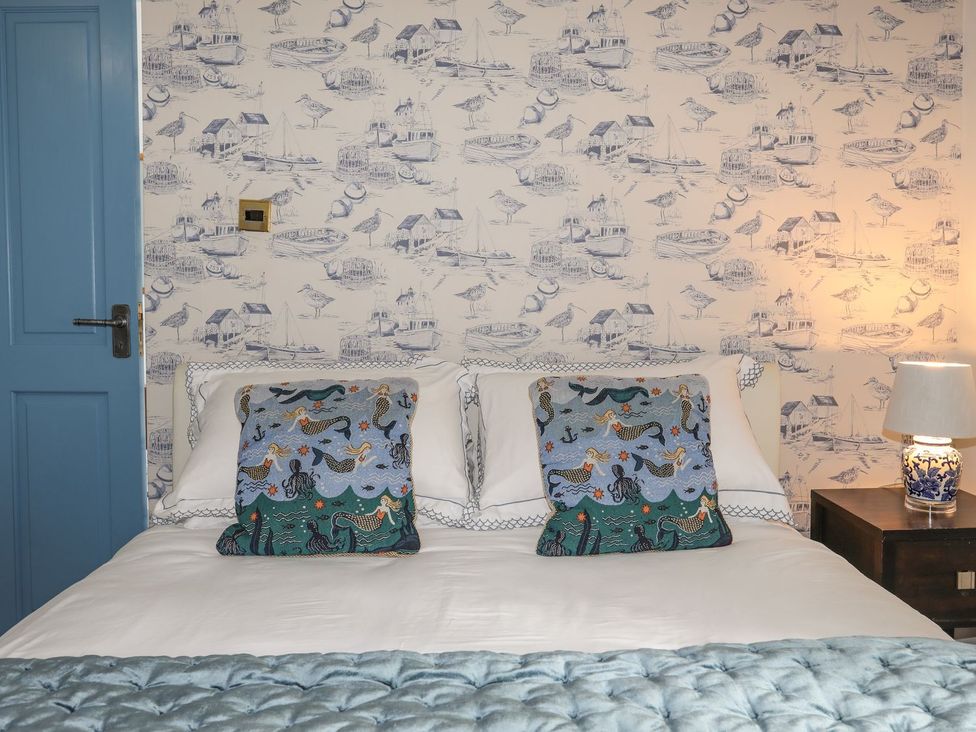 A bedroom with a bed and decorative pillows at Riverside Cottage in Caernarfon