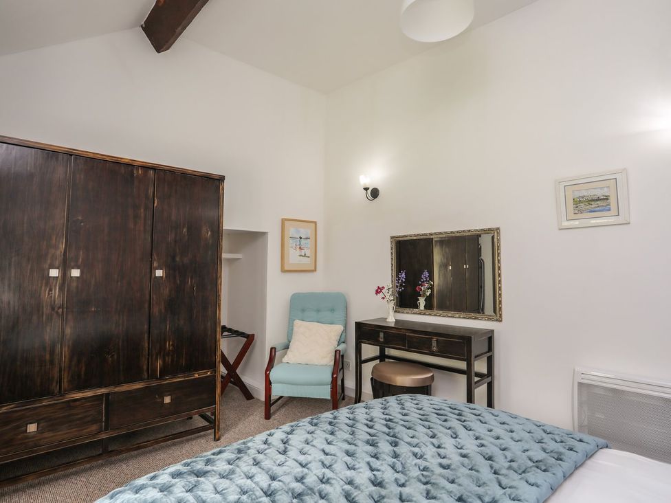 A bedroom with a wardrobe and a vanity table at Riverside Cottage in Caernarfon
