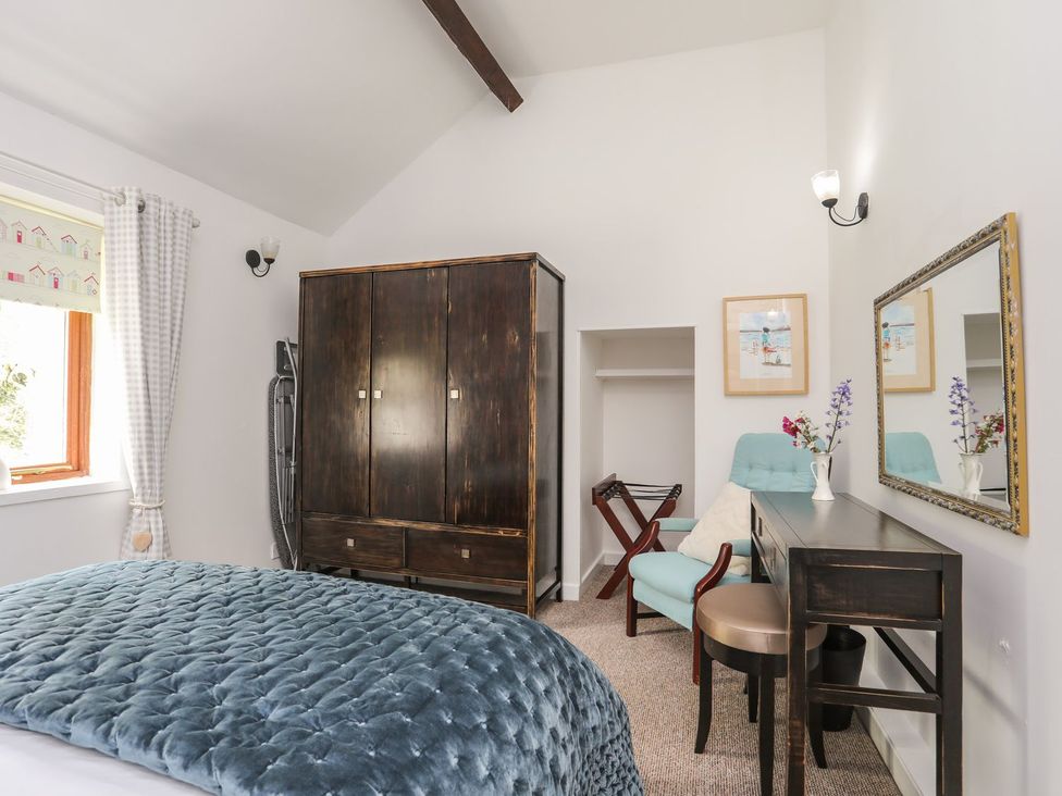 A bedroom with a bed, wardrobe, desk, and chair at Riverside Cottage in Caernarfon