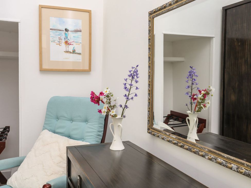 A living room with a chair and a flower vase at Riverside Cottage in Caernarfon
