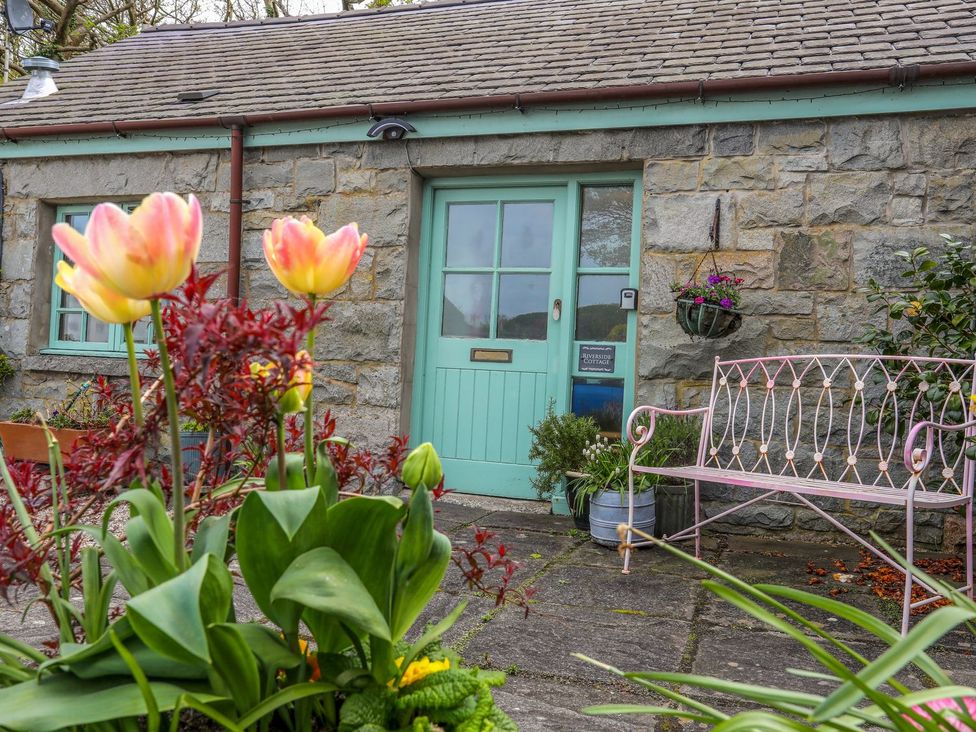 An outdoor area with flowers and a bench at Riverside Cottage in Caernarfon