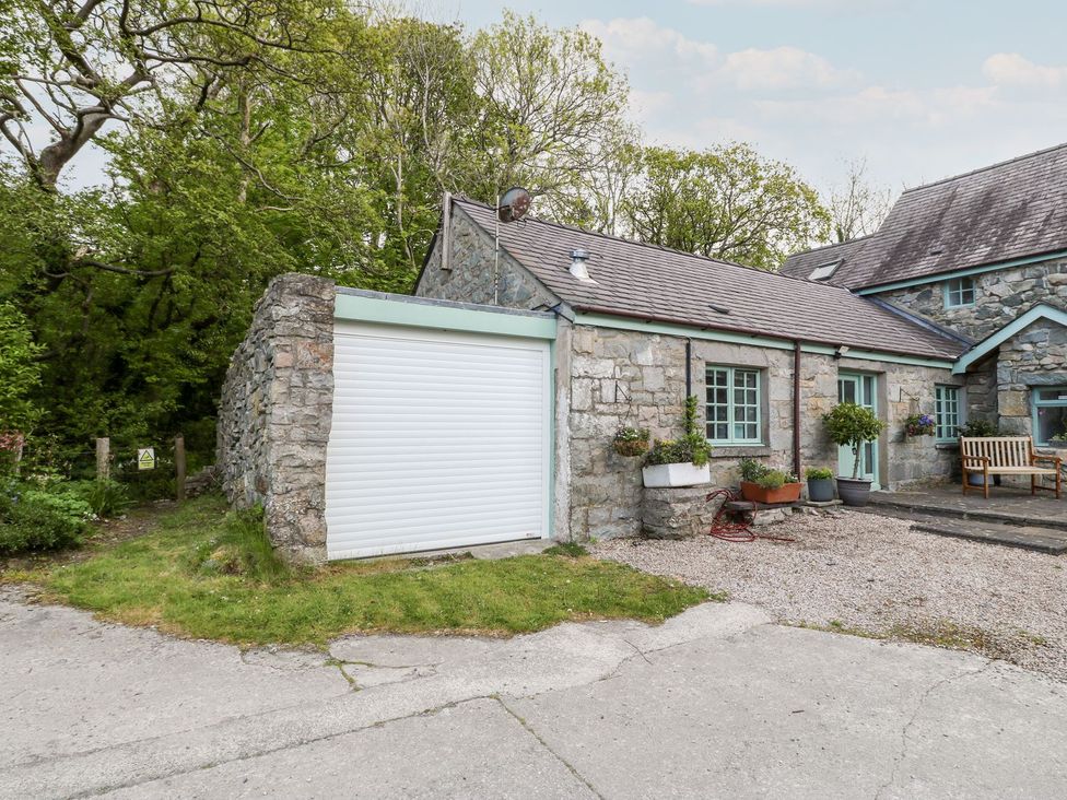A garage and stone wall with planters at Riverside Cottage in Caernarfon
