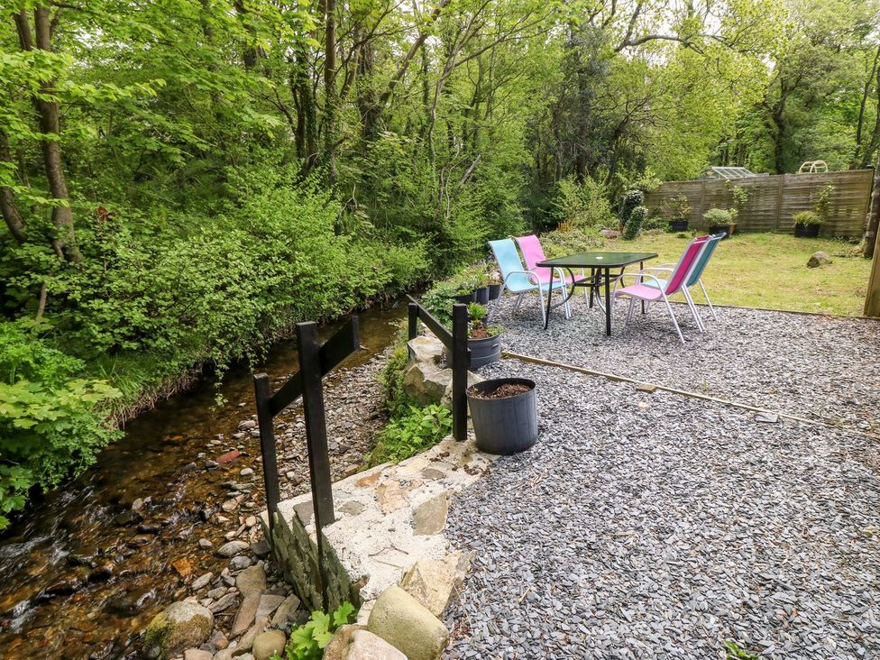 A garden with a table and chairs beside a stream at Riverside Cottage in Caernarfon