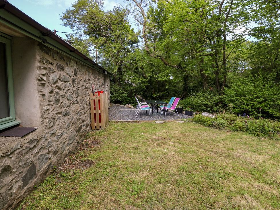 A garden with stone wall and chairs around a table at Riverside Cottage in Caernarfon