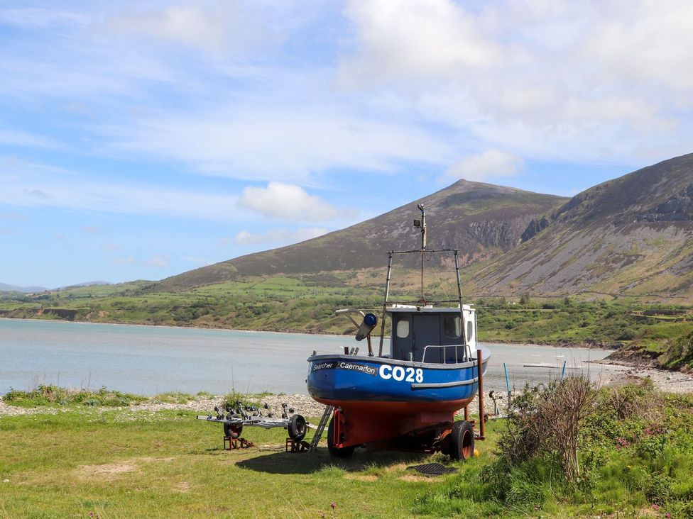 A boat near water with mountains in the background at Riverside Cottage in Caernarfon