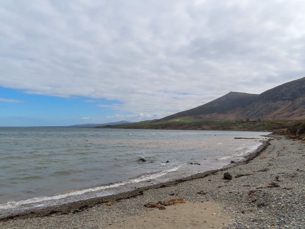 A beach with a shoreline and mountains in the background at Riverside Cottage in Caernarfon
