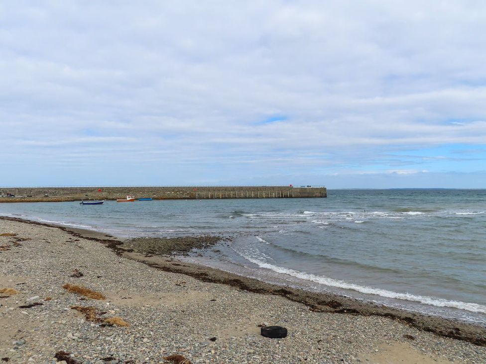 A beach with a pier and boats at Riverside Cottage in Caernarfon