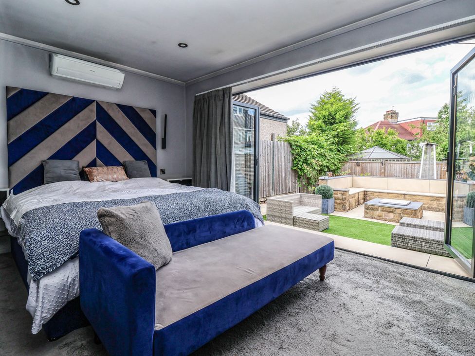 A bedroom with a bed and sliding doors leading to a garden at The Annexe in Shipley