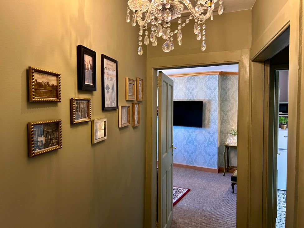 A hallway with framed pictures and a chandelier at Downton II in Alnwick