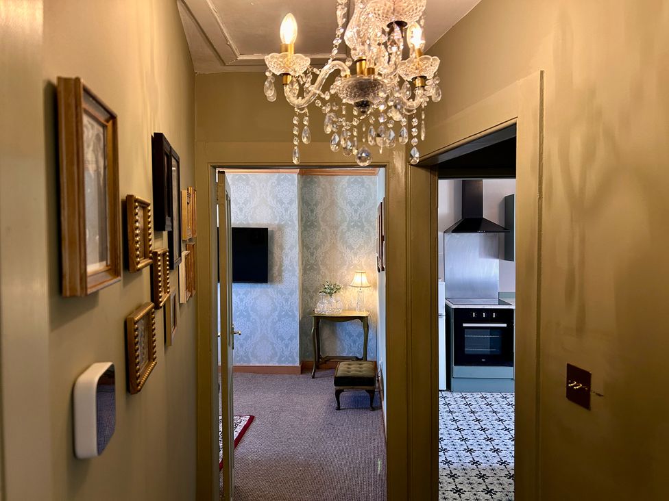 A hallway with a chandelier and kitchen access at Downton II in Alnwick