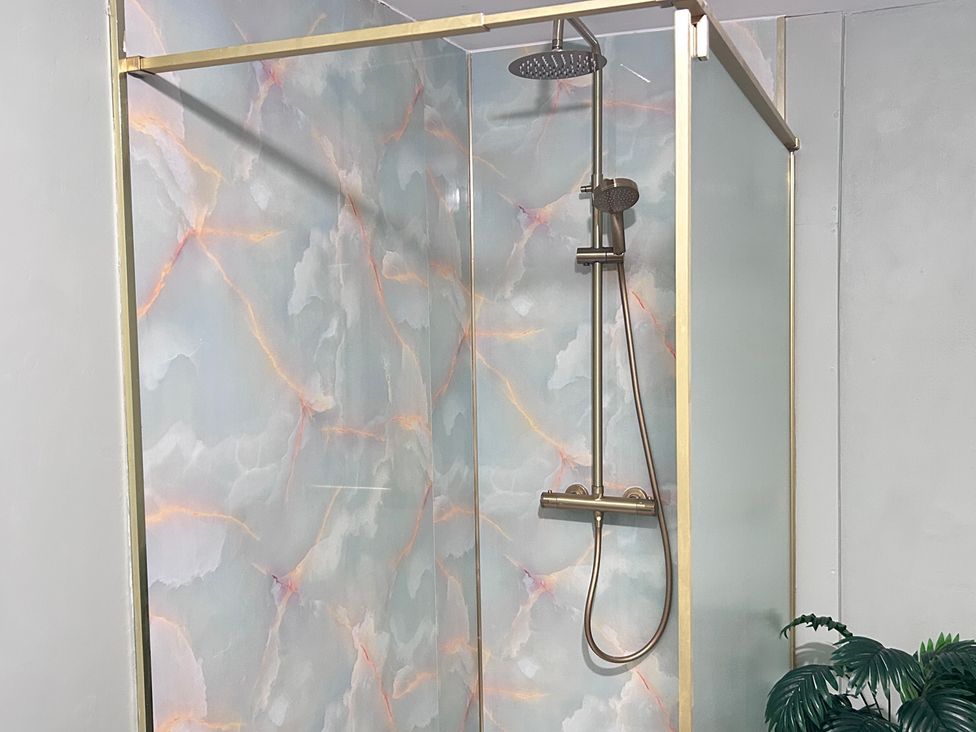 A shower with a glass door and a tiled wall at Downton II in Alnwick