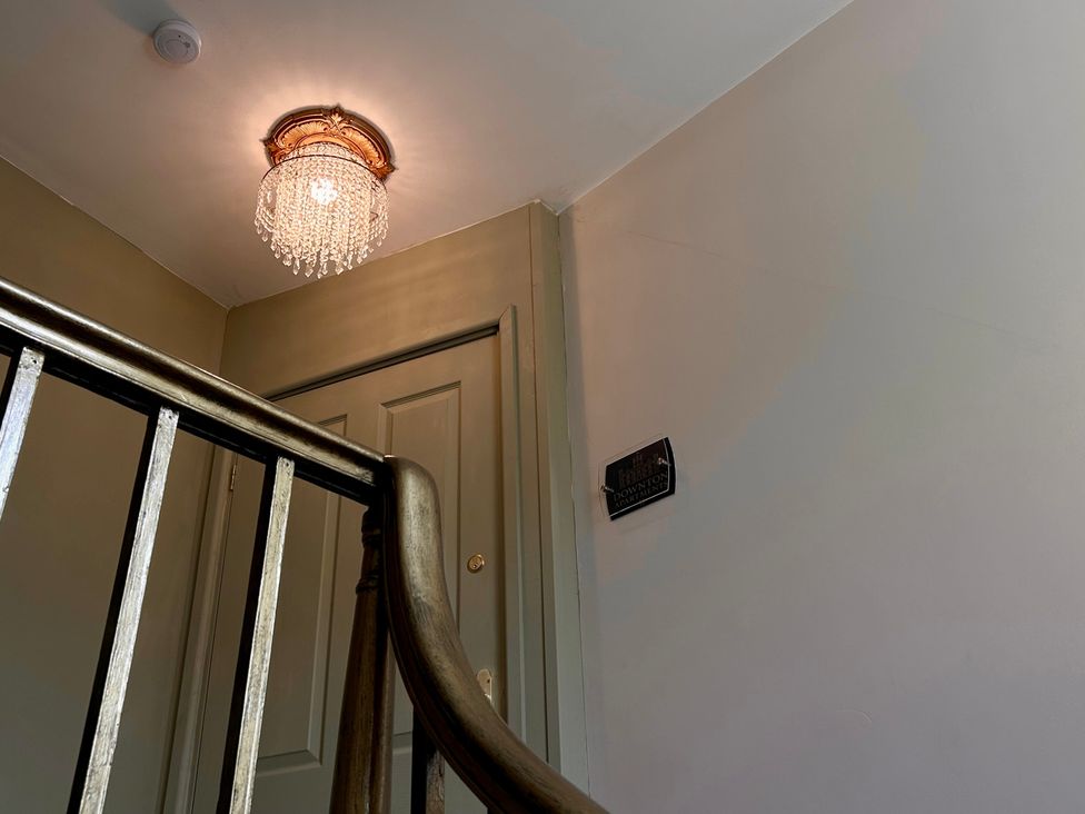 A staircase with a chandelier and a door at Downton II in Alnwick