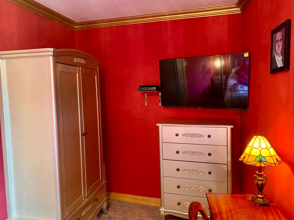 A bedroom with a wardrobe, television, dresser, and lamp at Downton II in Alnwick