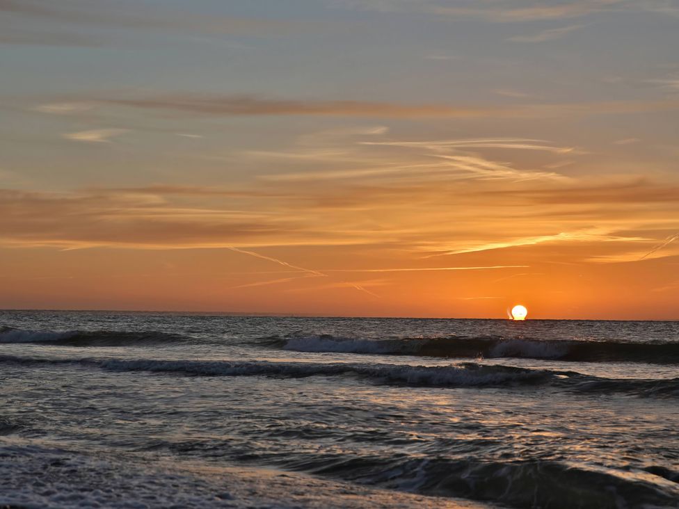 A sunset over the ocean with waves at No 1 The Martins Walberswick