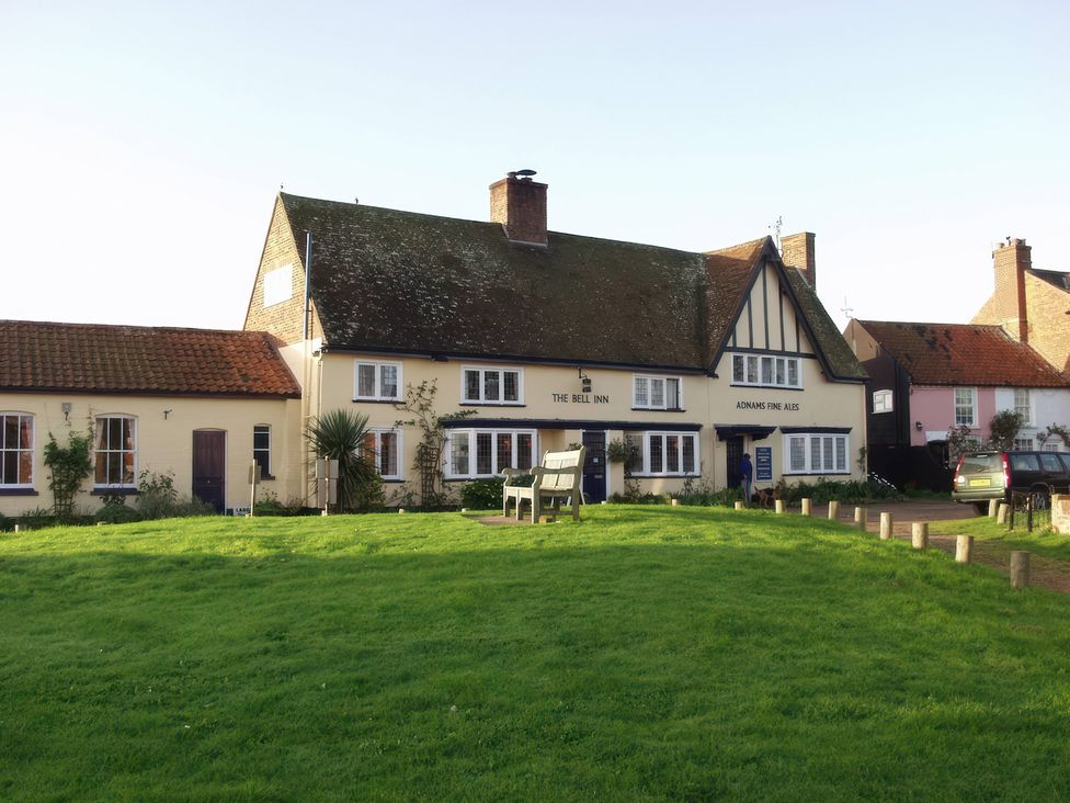 An inn with a sign and benches in front at No 1 The Martins Walberswick