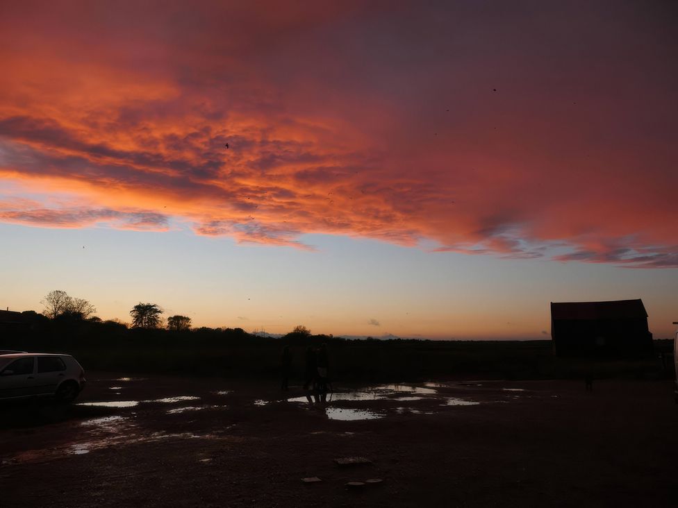 A silhouette of clouds and people with a barn at No 1 The Martins Walberswick
