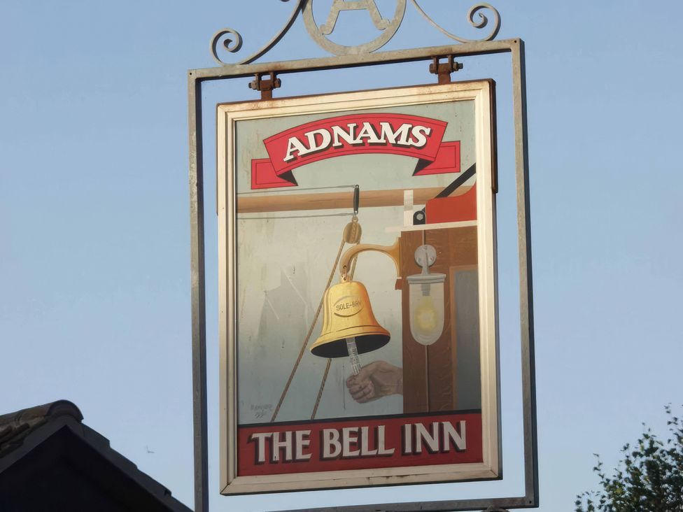 A sign depicting a bell and hand at The Bell Inn in Walberswick