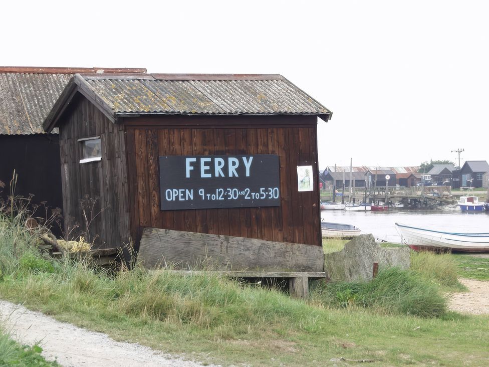 A wooden building with a ferry sign located by a river at No 1 The Martins in Walberswick