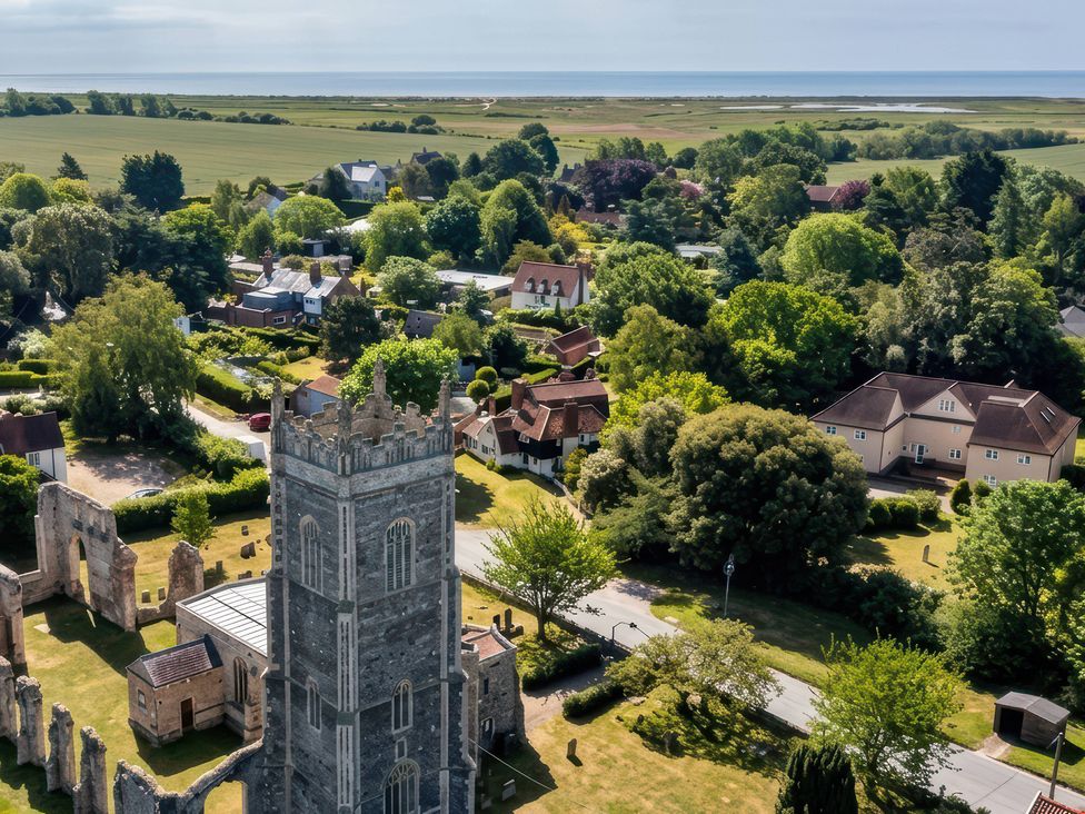 An aerial view of a church tower surrounded by houses and fields at No 1 The Martins in Walberswick