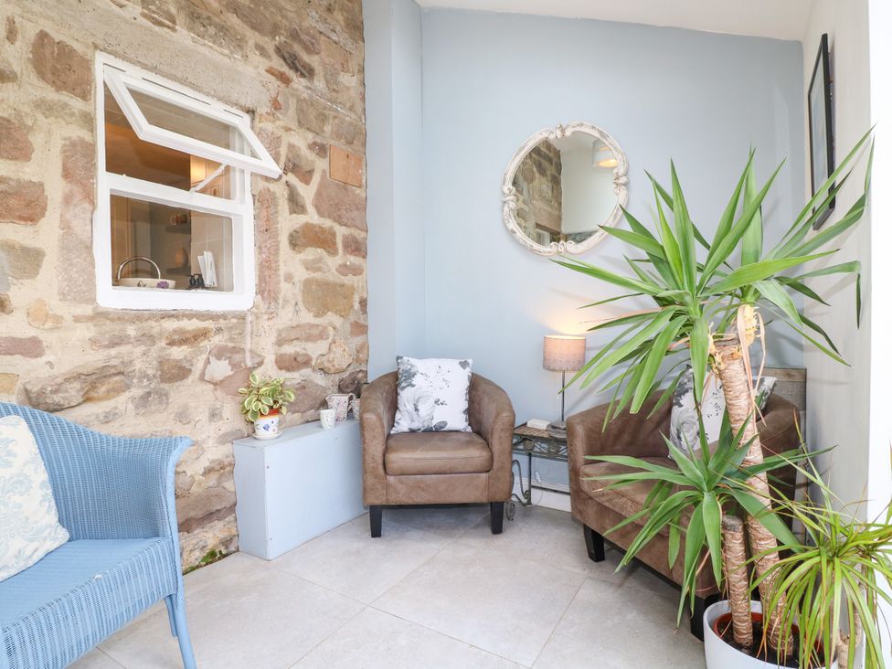 A snug area with armchairs, a plant, and a lamp at Sunnyside Elton