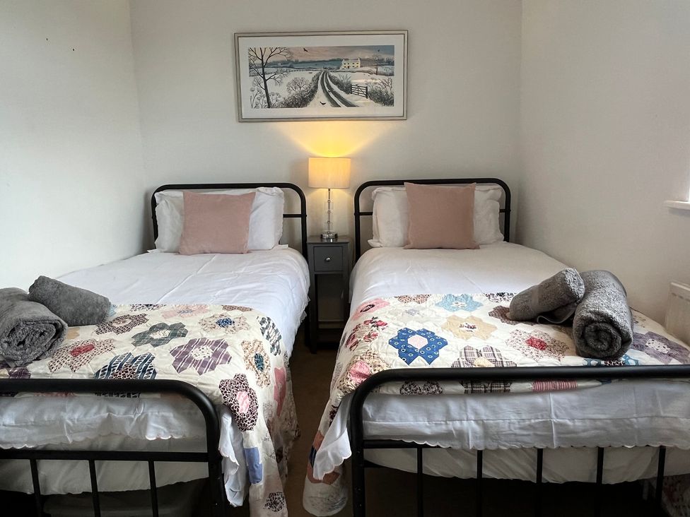 A bedroom with two beds and a bedside table at Sunnyside in Elton