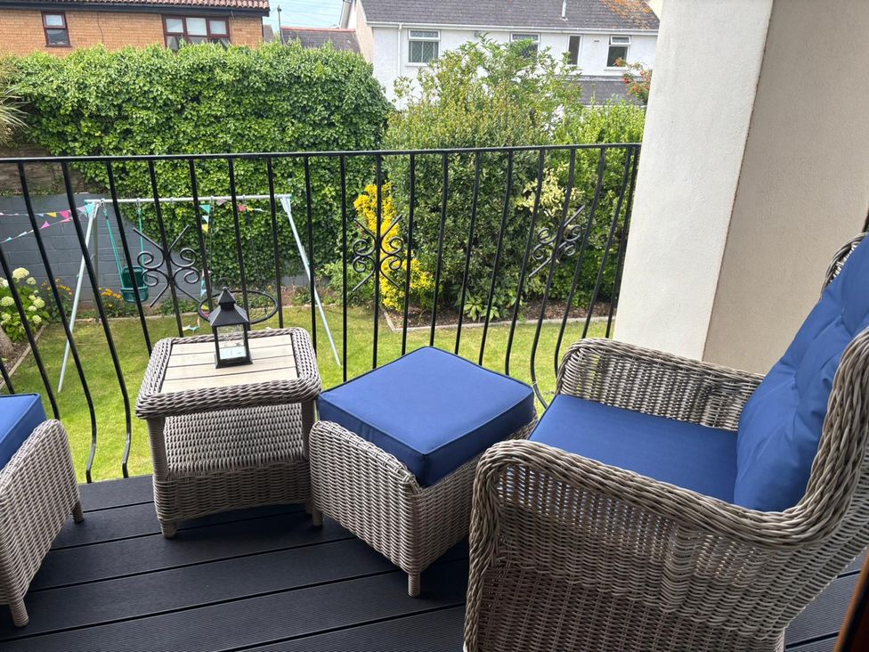 A balcony with wicker furniture and view of garden at 7 Adrian Close Porthcawl