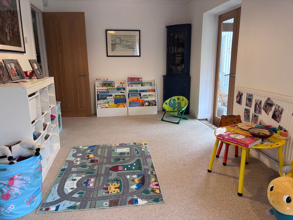 A playroom with a colorful carpet and bookshelves at 7 Adrian Close Porthcawl