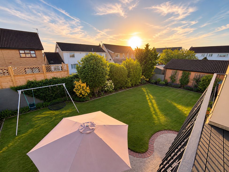 A garden with a swing set and a parasol at 7 Adrian Close in Porthcawl
