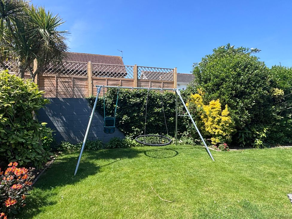 A garden with a swing set and grassy area at 7 Adrian Close Porthcawl