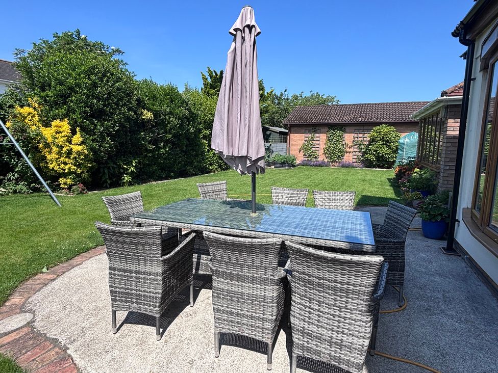 A table with chairs and an umbrella in a garden at 7 Adrian Close Porthcawl