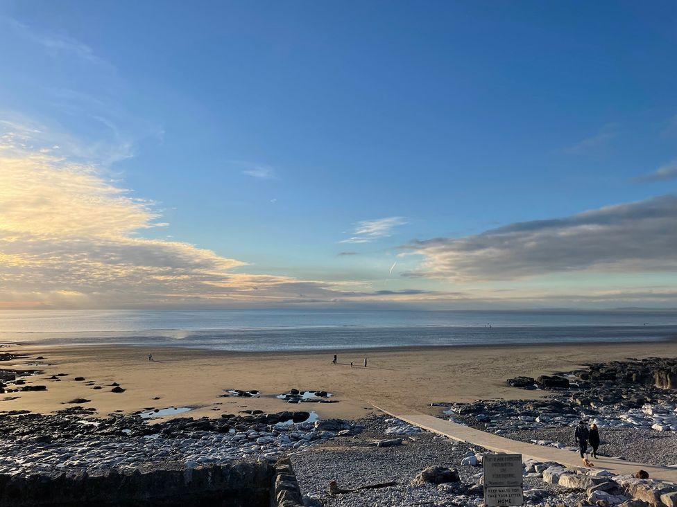 A beach with rocks and people walking at 7 Adrian Close Porthcawl